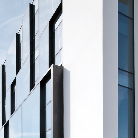 Close-up of a modern building exterior with large glass windows and a sleek white facade - Reynaers