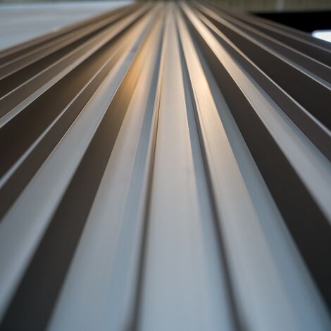 Close-up perspective of metallic panels extending into the distance, with light reflecting off the surface - Reynaers