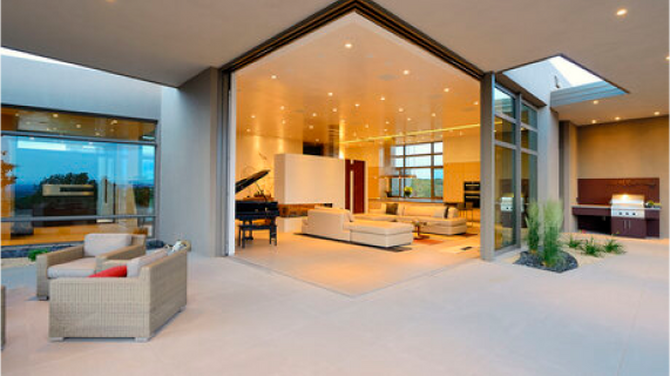 Spacious and modern open-concept living area with large sliding doors in a corner leading to an outdoor patio - Reynaers