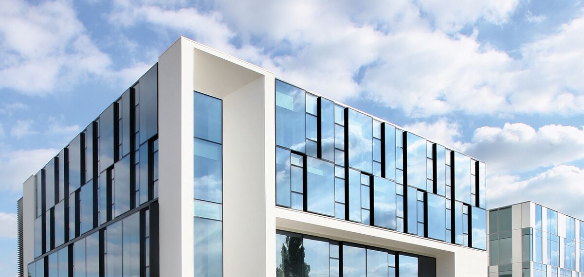 Modern building with large glass windows and clean white cubic structures - Reynaers
